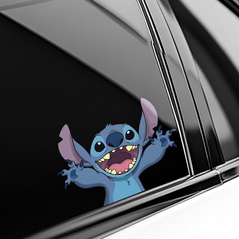 May include: A blue cartoon character sticker with large ears, a wide grin, and outstretched arms. The sticker is applied to a car window, with the character's face and arms visible. The background is a black car interior.