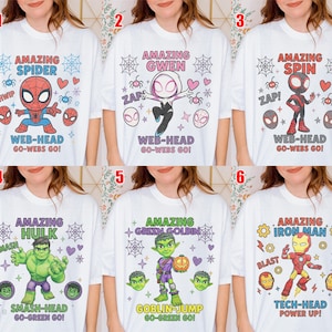 May include: A selection of white t-shirts, each adorned with a vibrant superhero design. The shirts showcase characters such as Spider-Man, Gwen, Spin, Hulk, Green Goblin, and Iron Man. Text includes character names and phrases.