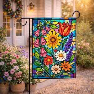 May include: A colorful garden flag with a stained-glass design. The flag features a vibrant array of flowers, including yellow daisies, red tulips, and pink bell-shaped blooms, set against a blue background. The flag is displayed outdoors on a black metal stand.