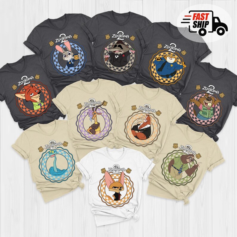 May include: A collection of Zootopia-themed t-shirts in various colors, including gray, tan, and white. Each shirt features a different character from the movie within a circular design, with the Zootopia logo at the top. The shirts are short-sleeved.