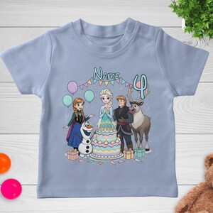 May include: A light blue t-shirt featuring a colorful graphic of characters from the movie Frozen. The design includes Elsa, Anna, Olaf, Kristoff, and Sven around a birthday cake with the number 4. The word "Name" is above the characters.