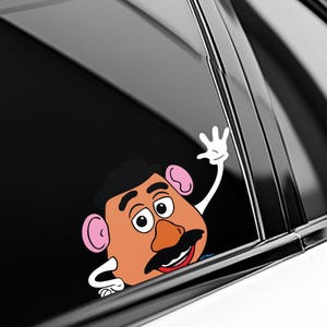 Peut inclure: Un autocollant color&eacute; repr&eacute;sentant un personnage de dessin anim&eacute; avec un grand nez orange, une moustache noire et des cheveux noirs. Le personnage fait signe avec une main gant&eacute;e blanche. L'autocollant est con&ccedil;u pour une vitre de voiture.