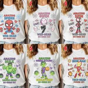 May include: White t-shirts featuring superhero designs. The shirts display characters such as Spider-Man, Gwen, Spin, Hulk, Green Goblin, and Iron Man. Each design includes character names and action phrases.