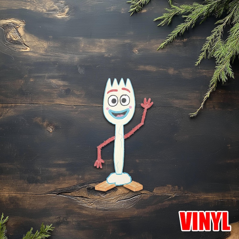 May include: A white and blue cartoon character resembling a spork, with red arms and feet, and a smiling face. The character is waving. The word "VINYL" is in red block letters in the bottom right corner. The background is a dark wood surface.
