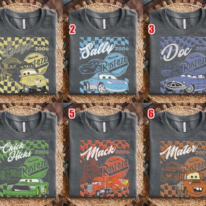 May include: Six charcoal gray t-shirts with different designs featuring characters from the movie Cars. Each shirt has a character's name, the year 2006, and the word "Rusteze". The characters include Luigi, Sally, Doc, Chick Hicks, Mack, and Mater.
