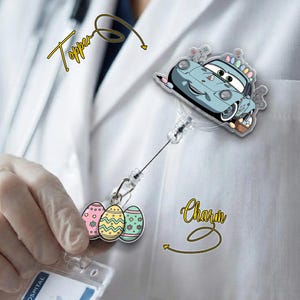May include: A light blue car-shaped badge reel topper with Easter egg accents. The reel also features a charm with three colorful Easter egg designs. The word "Topper" is written in cursive.