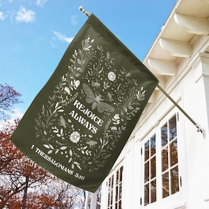 May include: A green garden flag with white floral designs and the text "Rejoice Always 1 Thessalonians 5:16".