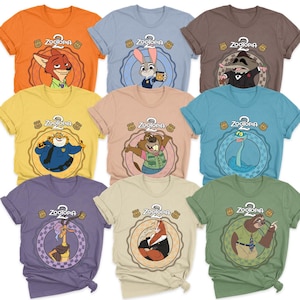 May include: A collection of colorful t-shirts featuring characters from the animated movie "Zootopia 2". Each shirt displays a different character within a circular design, with the movie's logo at the top. The shirts are in various colors, including orange, blue, and green.