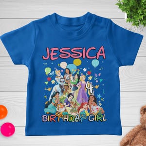 May include: A blue toddler t-shirt featuring a colorful graphic of Disney princesses. The name "JESSICA" is printed in pink above the graphic, with the number "4" and the words "BIRTHDAY GIRL" below.