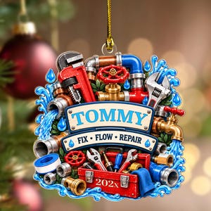 May include: A decorative hanging ornament featuring plumbing tools, pipes, and water splashes. A central banner displays the name TOMMY and the text FIX FLOW REPAIR. A red toolbox at the bottom is labeled 202x. The design includes a red pipe wrench, a brass faucet, and various metal fittings.