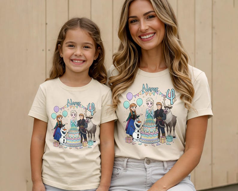 May include: Two beige t-shirts with a colourful graphic featuring characters from the movie Frozen, a birthday cake, and the number 4. The shirts are worn by a mother and daughter.