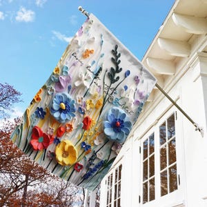 May include: A white garden flag with a colorful floral design and the text "Basic human rights are not negotiable".