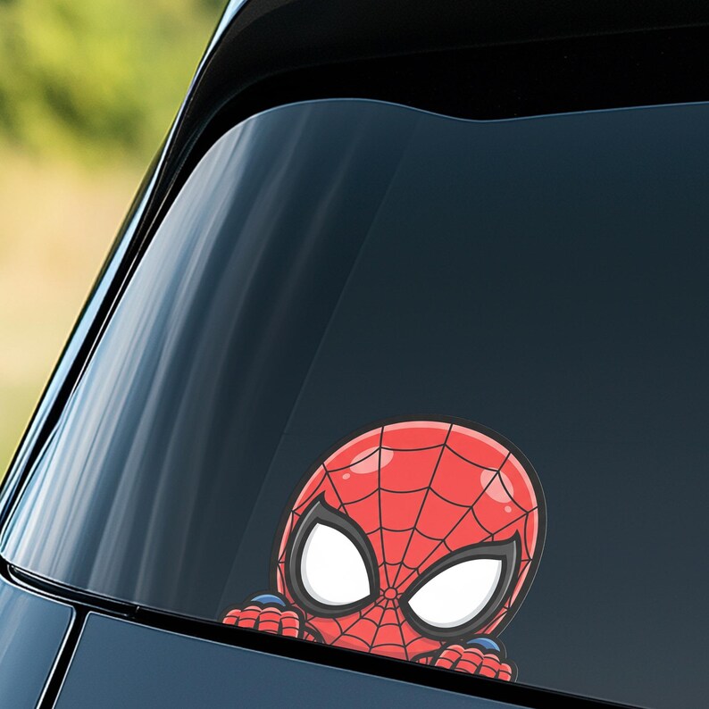 May include: A red and black Spider-Man car window decal. The decal features a cartoon version of Spider-Man's head and mask, with large white eyes and a web pattern. The decal is peeking over the edge of a car window.