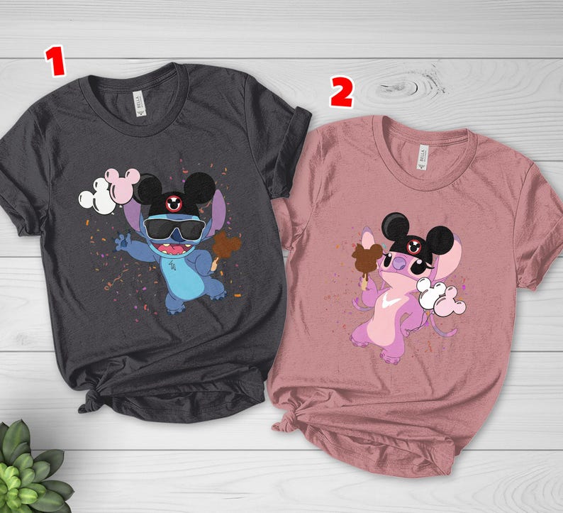 K&ouml;nnte beinhalten: Zwei T-Shirts, eines in Anthrazit und eines in Staubrosa, jeweils mit einer Cartoonfigur, die eine Sonnenbrille und einen Mickey-Mouse-Hut tr&auml;gt. Die blaue Figur h&auml;lt ein Eis und Luftballons, w&auml;hrend die lila Figur ein Eis und Luftballons h&auml;lt.