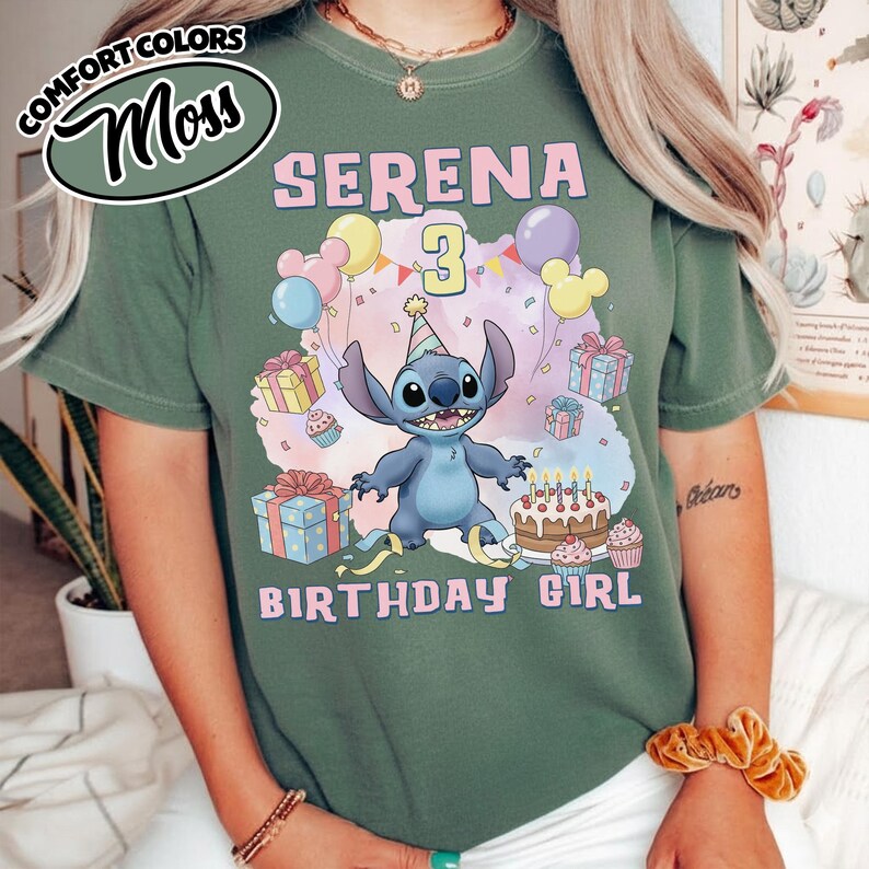 Peut inclure: Un t-shirt vert sauge avec une illustration du personnage Stitch portant un chapeau de f&ecirc;te, entour&eacute; de ballons color&eacute;s, de cadeaux, d'un g&acirc;teau d'anniversaire et de confettis. Le texte indique SERENA 3 BIRTHDAY GIRL en lettres roses et jaunes.