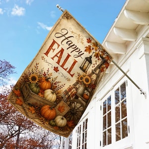 May include: A rectangular garden flag featuring the text Happy FALL in brown script and block letters. The design includes orange and green pumpkins in a wooden crate, sunflowers, autumn leaves, a lantern, and a wooden wagon wheel.