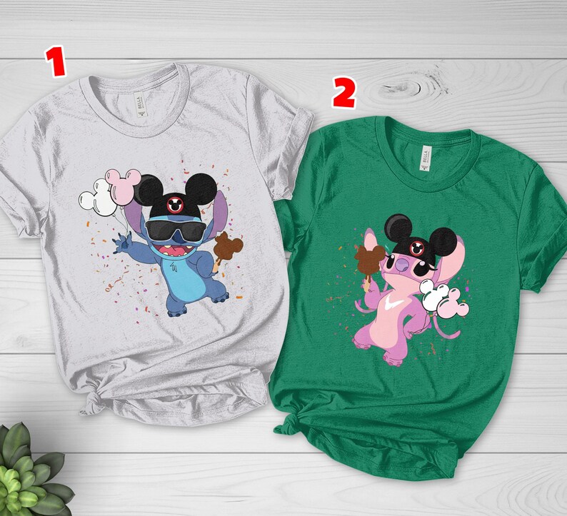 K&ouml;nnte beinhalten: Zwei kurz&auml;rmelige T-Shirts mit Zeichentrickfiguren. Eines ist wei&szlig; mit einer blauen Figur, die eine Sonnenbrille und einen Hut tr&auml;gt und Luftballons und einen Leckerbissen h&auml;lt. Das andere ist gr&uuml;n mit einer rosa Figur, die einen Leckerbissen und Luftballons h&auml;lt.