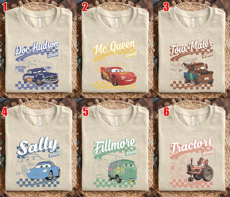 May include: A collection of six beige t-shirts featuring Disney Pixar Cars characters. Each shirt displays a character name, the year 2006, a checkered pattern, and a graphic of Doc Hudson, Mc Queen, Tow Mater, Sally, Fillmore, or Tractors.