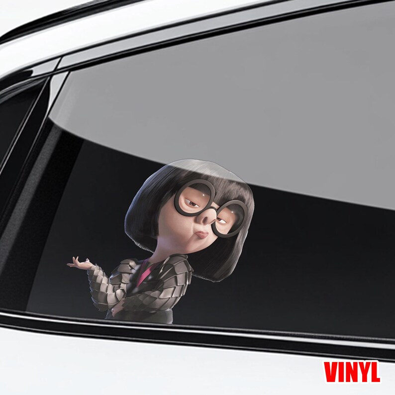 May include: A white ceramic mug with a black handle and the text "But First, Coffee" in a bold, black font. The mug is set against a blurred background. The mug appears to be approximately 10 cm tall.