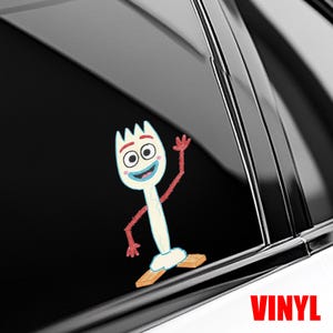 May include: A white and red cartoon character sticker with a fork-like head, waving with red arms and hands. The character is standing on two wooden blocks. The word "VINYL" is printed in red at the bottom.