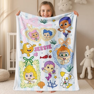 May include: A white and light blue striped fleece blanket featuring Bubble Guppies characters, including Molly, Gil, Goby, Deema, Oona, Nonny, and Bubble Puppy. The design includes decorative frames, sea life, stars, and the name Jessie in pink text.