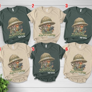 May include: Six short-sleeved t-shirts in different colours, each with a Zootopia cartoon graphic. The shirts display family member names on safari hats, with the text "ZOOTOPIA TRIP 2026" beneath the graphic.