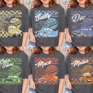 May include: Six charcoal gray t-shirts featuring characters from the movie Cars. Each shirt has a different character's name, the year 2006, and the Rusteze logo. The characters include Luigi, Sally, Doc, Chick Hicks, Mack, and Mater.