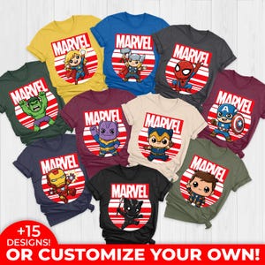Pode incluir: Uma cole&ccedil;&atilde;o de camisetas com tema Marvel em v&aacute;rias cores, cada uma com um personagem de super-her&oacute;i diferente. As camisetas exibem o logotipo da Marvel dentro de um design circular vermelho e branco. O texto na parte inferior diz "+15 DESIGNS! OR CUSTOMIZE YOUR OWN!"