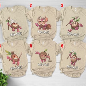 Puede incluir: Seis camisetas beige con gr&aacute;ficos de monstruos de dibujos animados. Cada camiseta presenta un dise&ntilde;o de monstruo diferente en tonos de marr&oacute;n, rosa y verde. La palabra "NAME" est&aacute; impresa debajo de cada personaje. Las camisetas son de manga corta y tienen cuello redondo.