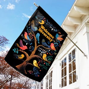 May include: A black garden flag with a tree and colorful birds. The text "Welcome Diversity" is written on the flag.
