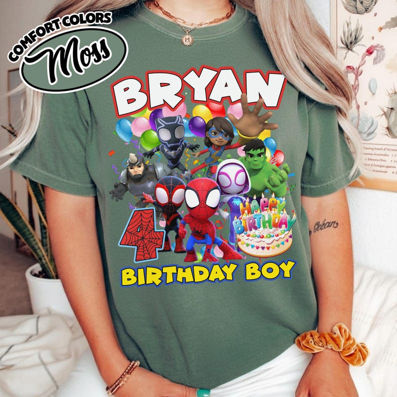 May include: A moss green t-shirt featuring a graphic print of Marvel superheroes including Spider-Man, Hulk, and Black Panther. The text reads BRYAN, 4, and BIRTHDAY BOY, along with a birthday cake illustration and colorful balloons.