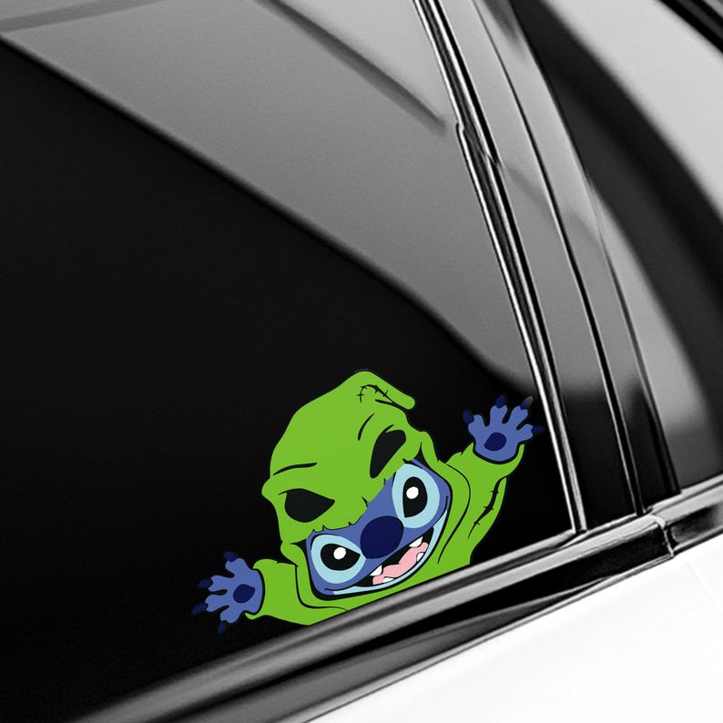 May include: A colorful vinyl decal featuring a cartoon character in a green hooded costume. The character has blue skin, large eyes, and a wide smile. The decal is designed to be applied to a car window.
