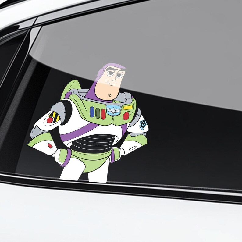 K&ouml;nnte beinhalten: Ein farbenfroher Vinyl-Aufkleber von Buzz Lightyear aus Toy Story. Der Aufkleber zeigt die Figur in ihrem charakteristischen gr&uuml;nen, wei&szlig;en, lila und schwarzen Raumanzug mit verschr&auml;nkten Armen. Der Aufkleber ist auf einer Autoscheibe angebracht.