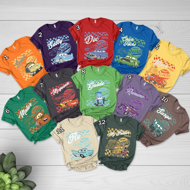 May include: A collection of twelve colorful t-shirts featuring various characters and designs from the animated movie "Cars." Each shirt displays a different character's name, the year 2006, and the "Rusteze" logo. The shirts are in various colors, including orange, purple, red, blue, yellow, green, and brown.