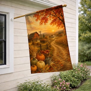 May include: A vertical garden flag featuring a rural autumn landscape with a red barn, a winding dirt path, and a sunset sky. The foreground displays a collection of orange and green pumpkins, wheat stalks, and a metal bucket on the ground.