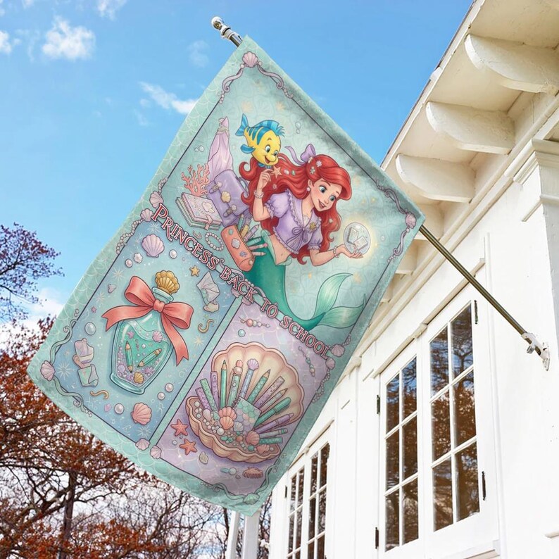 Puede incluir: Bandera decorativa para exteriores con una ilustraci&oacute;n de sirena de pelo rojo y un pez amarillo. La bandera tiene un fondo azul claro con el texto "PRINCESS BACK TO SCHOOL". Tambi&eacute;n presenta un frasco de perfume y brochas de maquillaje.