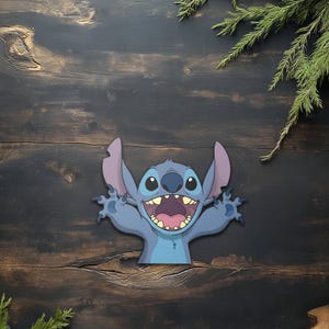 May include: A blue cartoon character with large ears and a wide grin, set against a dark wood background. The character has a light blue body, darker blue accents, and a pink mouth. Green sprigs are in the corners.