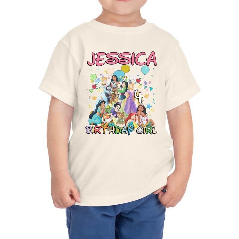 May include: A cream-colored toddler t-shirt featuring the name "JESSICA" in pink bubble letters above a graphic of Disney princesses. The number "4" is next to the princesses, with the words "BIRTHDAY GIRL" below.