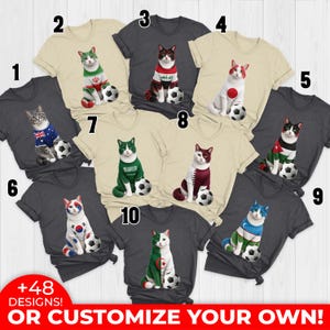May include: A collection of t-shirts featuring cat illustrations dressed in the colors of various national flags, each posed with a soccer ball. The shirts are in various colors, with text at the bottom that says "+48 DESIGNS! OR CUSTOMIZE YOUR OWN!"