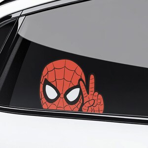Pu&ograve; includere: Un adesivo per auto di Spider-Man rosso e nero. L'adesivo mostra la testa e la mano di Spider-Man che fa il segno della pace. L'adesivo &egrave; su un finestrino dell'auto.