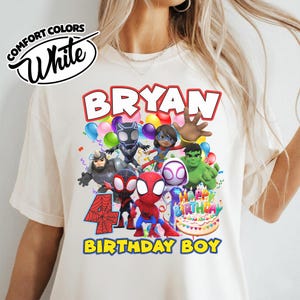 May include: A cream-colored t-shirt featuring a graphic print of various superhero characters, a large red number 4, a birthday cake, and the text BRYAN HAPPY BIRTHDAY BIRTHDAY BOY. The top left corner displays a logo with the text COMFORT COLORS White.