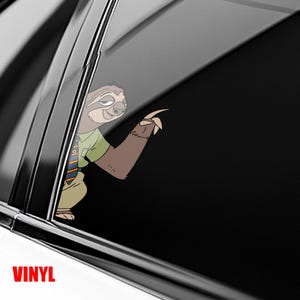 May include: A vinyl decal featuring a cartoon sloth character from Zootopia, wearing a green shirt and tie, peeking out from behind a car window. The word "VINYL" is printed in red at the bottom.