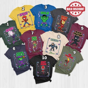 May include: Ten different t-shirts in various colours, each showcasing a superhero character. The shirts feature characters such as Gwen, Spidey, Hulk, Iron Man, Black Panther, Green Goblin, Doc Ock, Rhino, Ms. Marvel, and Ant-Man, with their names and graphics.