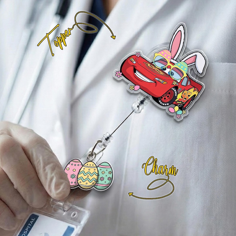 May include: A red Lightning McQueen badge reel topper with bunny ears and sunglasses, and a charm with three Easter eggs. The topper and charm are attached to a retractable reel. The word "Topper" is written above the topper and the word "Charm" is written below the charm.