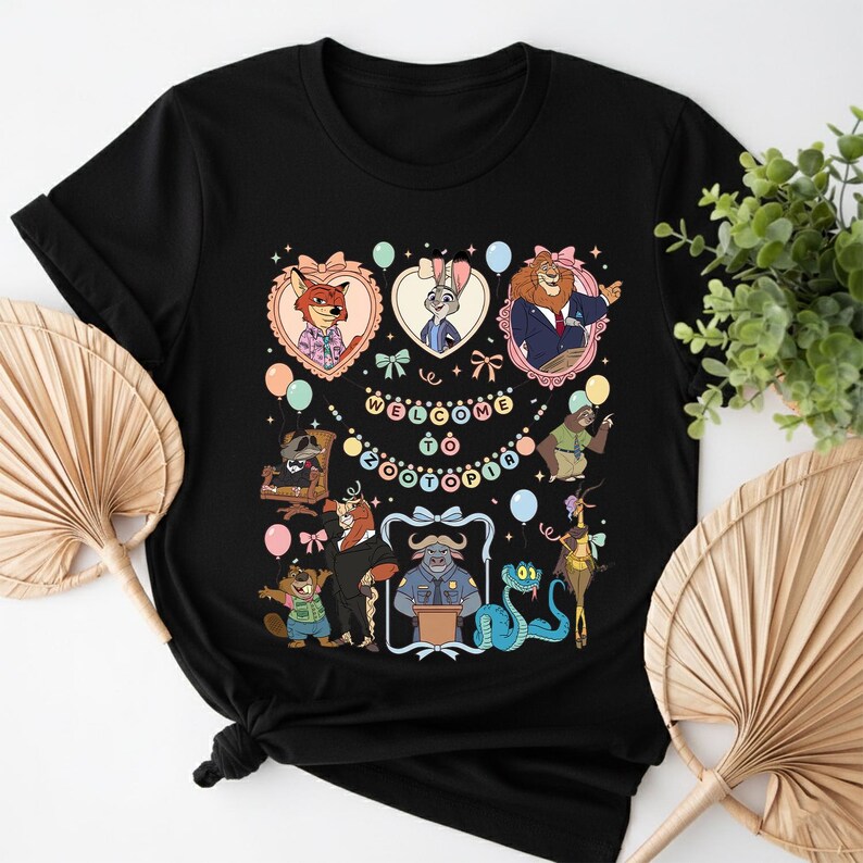 K&ouml;nnte beinhalten: Schwarzes T-Shirt mit Cartoon-Charakteren aus Zootopia, darunter Nick Wilde, Judy Hopps und B&uuml;rgermeister Lionheart, umgeben von Luftballons und dem Text "Welcome to Zootopia". Das Design ist farbenfroh und skurril, perfekt f&uuml;r Fans des Animationsfilms.