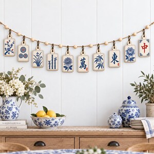 May include: A decorative garland featuring ten rectangular wooden tiles suspended from a jute string with wooden beads. Each tile displays blue and white illustrations of floral patterns, bamboo, and Chinese characters, including the red character 中.