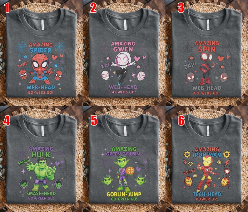 May include: Six dark grey t-shirts with superhero designs. Each shirt features a different character: Spider-Man, Spider-Gwen, Spider-Spin, Hulk, Green Goblin, and Iron Man. Text includes character names and phrases like "Web-Head" and "Smash-Head."