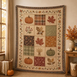 May include: A rectangular woven throw blanket featuring a grid pattern of autumn-themed squares. The design includes illustrations of orange and green pumpkins, red maple leaves, acorns, wheat stalks, and various plaid and floral fabric patterns.