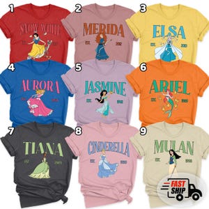 May include: A collection of nine colorful t-shirts featuring various Disney princess designs. Each shirt displays a princess's name, an illustration, and the year of their debut. The shirts are in various colors, including red, blue, and orange.
