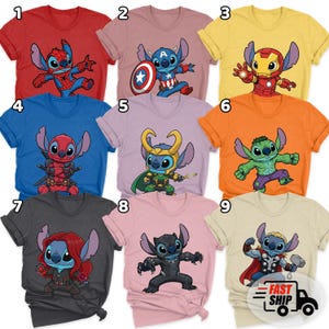 May include: A collection of nine colorful t-shirts featuring cartoon character Stitch in various superhero costumes. The shirts are in a variety of colors, including red, pink, yellow, blue, orange, and gray. Each shirt has a different design.